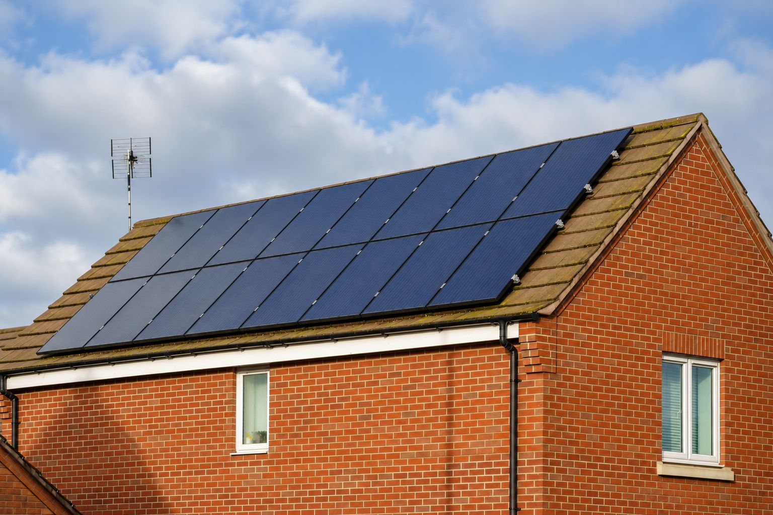 Illustrative solar panels on the tiled roof of an English brick house